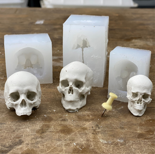 Skull-shaped molds and casts on a wooden surface