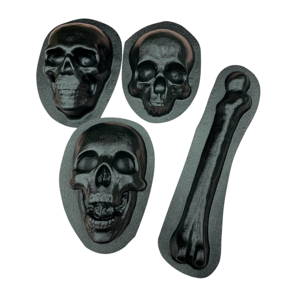 A set of four black ABS plastic molds, including three skull shapes and one femur bone shape, displayed on a white background.