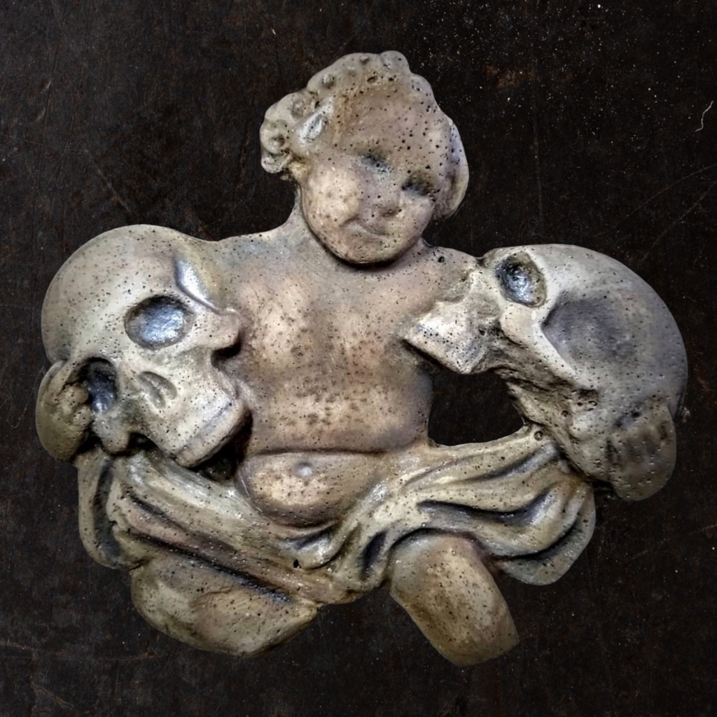 A mold of a cherub holding two skulls, used for creating a plaster replica.