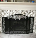 Set of white plaster skull castings arranged decoratively around a fireplace with black metal screen, showing finished results from Pacific Mold Design skull fireplace mold set