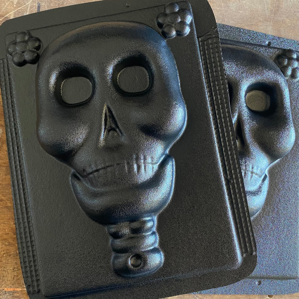 A black ABS mold relief of a skull, likely used for casting concrete or plaster for Day of the Dead decorations.