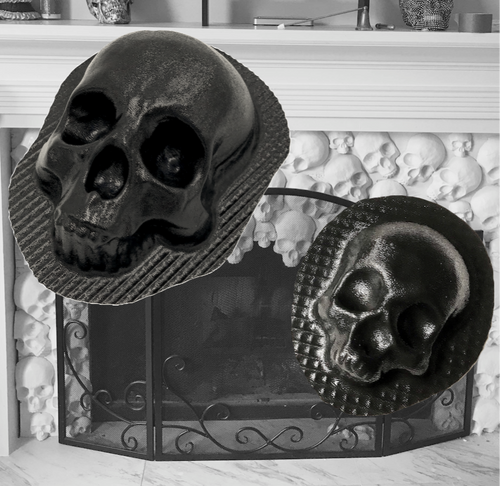 Set of white plaster skull castings arranged decoratively around a fireplace with black metal screen, showing finished results from Pacific Mold Design skull fireplace mold set